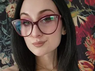 KatieLenore poses with a close-up headshot, showing her dark hair and pink-tinted glasses.