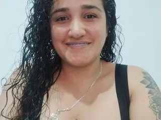 KattyX27 smiles while showing her wet, curly dark hair and bare shoulders in a close-up shot.