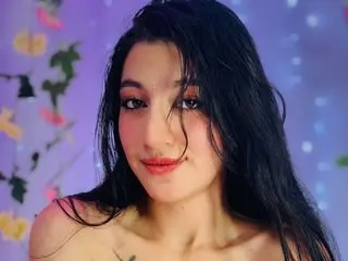 KattyyQueenn poses with long dark hair, showing her bare shoulders and chest against a soft purple background.