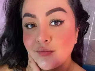 KatyPersian looks into the camera with a soft smile and dark wavy hair in a close-up selfie.