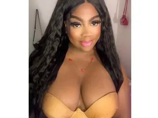 KeiillyBrown poses with long dark hair, wearing a tan bra that shows off her cleavage and cleavage-heavy bust.