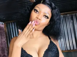 Kgade99 pouts her lips and poses in a black lace bra with her hand near her face.