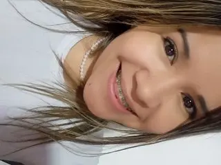KhloeMilkExtreme smiles close up, showing her long brown hair and teeth while looking directly at the camera.