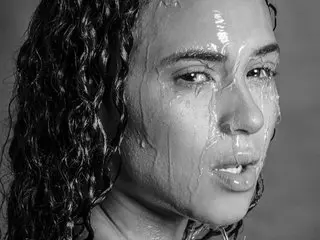 Kim_Stonne has wet, curly hair and a wet face, looking directly at the camera with a direct gaze.