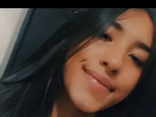 KiraaMoon69 smiles close to the camera, showing her long dark hair and face in a close-up shot.