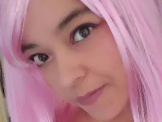 KumaChan — KumaChan looks into the camera with a soft expression, wearing long pink hair and pink lipstick.