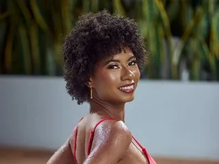 KylieDecks — KylieDecks smiles while posing in a red bikini with her curly hair down outdoors.