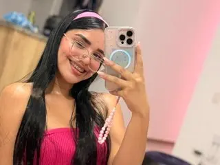 Smiling young woman in a pink top and headband taking a happy mirror selfie indoors.