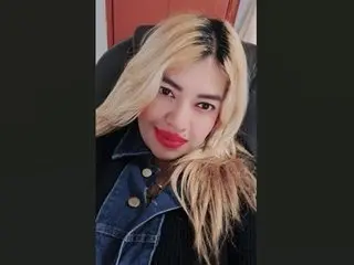 Smiling blonde woman in a denim jacket and black top posing for a portrait indoors.