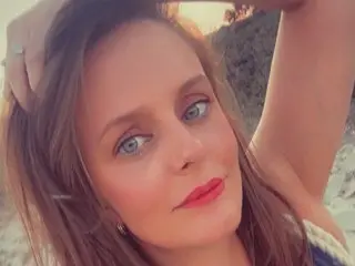 LadyLouisa188 poses closely for a selfie, showing her face, long brown hair, and red lipstick against a soft, natural outdoor background.