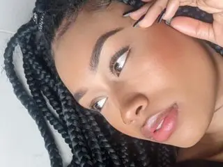 Laia_strom19 poses for a close-up selfie, looking off to the side with her long black braids framing her face.