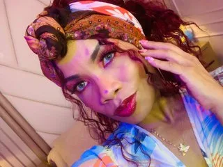 LailaDavidson wears a colorful patterned headband and looks into the camera with red hair and bright blue eyes.