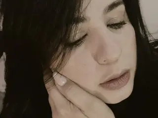 LauraCastaneda poses with her eyes closed, resting her hand against her cheek and neck, showing her dark hair and face.