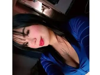 LauraHillx poses with long dark hair and a deep blue top, showing her cleavage and smiling at the camera.