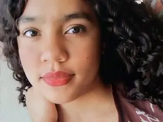 Lauradani poses close-up, showing her face and dark curly hair against a plain background.