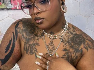 LaylaCumninngss poses with glasses and silver necklaces, showing off her large floral tattoos and nose ring.