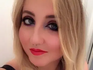 LaylaRaven poses close-up with blonde hair and heavy eye makeup, looking directly at the camera with red lipstick.