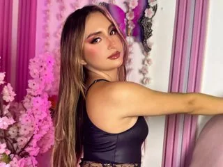 Leah_moon11 — Leah_moon11 poses in a black tank top with long blonde hair against a pink floral background.