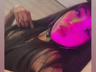 LeilaaIvy lies on her back with long dark hair spread out and pink light glowing on her face.