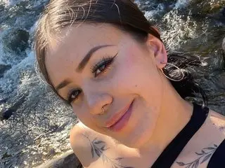 Lexie_Storm smiles while looking at the camera, showing her dark hair and black tank top strap against her skin.