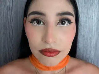 Lexxalove looks into the camera with heavy eyeliner and red lipstick, wearing an orange choker.