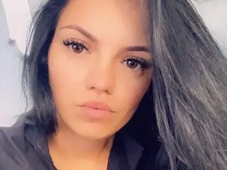 Lexy_sweet19 poses close-up, looking at the camera with long dark hair and heavy eyelashes.