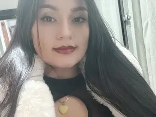 LhindaCarter poses with long black hair and dark red lipstick, wearing a white fluffy collar or trim.