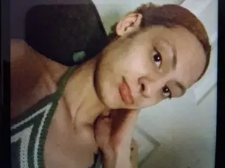 Lianalee143 poses with her hand near her neck, showing her face and shoulders while wearing a green and white striped top.