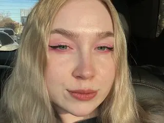Lily_Flower69 poses with a close-up headshot, showing her blonde hair and light eye makeup in a natural setting.