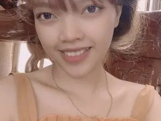 LindaGirl68 smiles while wearing a thin orange tank top, showing her face, neck, and shoulders in a close-up shot.
