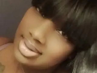Lippz poses close-up, showing her face, dark hair, and lips against a plain background.