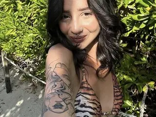 LizzyHope poses outdoors in sunlight, wearing a low-cut tiger print top that shows cleavage, with her dark hair falling over her shoulders.