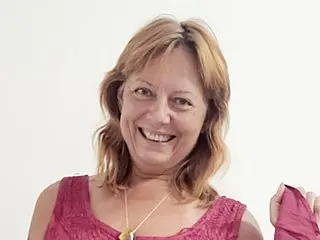 LoizaShafran smiles while wearing a pink tank top, showing her light brown hair and neck against a plain white background.