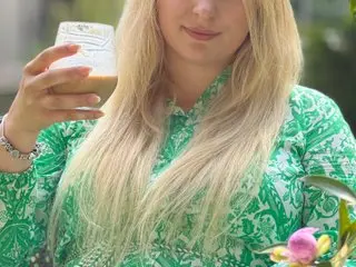 Lola_Bunny_Hot poses with her long blonde hair down, wearing a green and white patterned top while holding a glass.