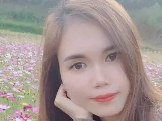 Young woman with long brown hair smiling peacefully in a dreamy field of pink cosmos flowers.