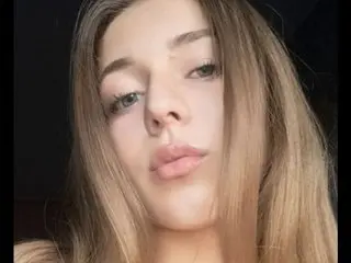 LoveDovee poses close-up, showing her face and long blonde hair against a dark background.