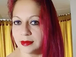 Lua_Evans poses close-up with her long red hair, showing her face and eyes against a yellow curtain background.