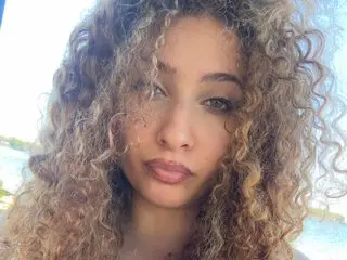 LuluToofire poses with her long, curly blonde hair framing her face in a close-up headshot.