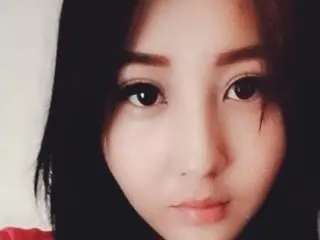 Close-up portrait of a young woman with long dark hair and natural makeup looking calmly at the camera.