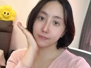 LunaCocoa poses with one hand against her cheek, showing her face and shoulders while wearing a pink ribbed top.