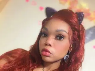 LunaNova444 poses close-up with long red hair and cat ears, looking directly at the camera with a neutral expression.