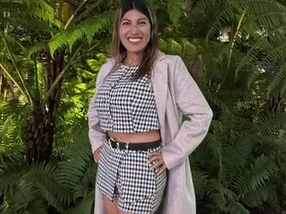 Lunabeya — Lunabeya stands in front of green tropical leaves wearing a black and white checkered crop top and matching skirt with a black belt.
