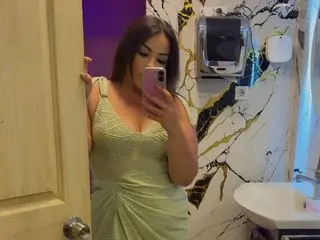 LusciousLolaxxo poses in a light green ribbed tank top, looking at the camera in a bathroom setting with marble-patterned walls.