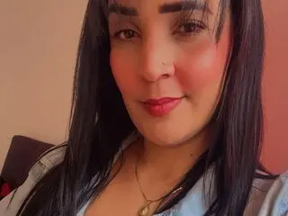 MILAHOT23 poses close-up, showing her long dark hair and red lipstick against a plain pink background.