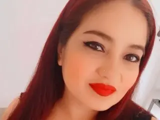 MILFMEGA poses with a direct gaze, showing her long red hair and bright red lipstick against a plain white background.