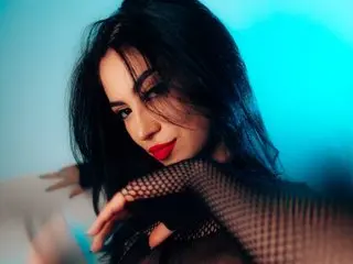 Moody portrait of a brunette woman in black fishnet clothing against a vibrant blue neon background.