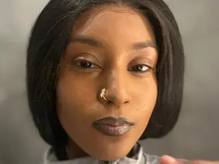 MadamP looks into the camera with a close-up view of her face, dark hair, and nose ring.