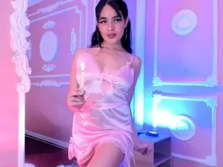 Young woman in a pink satin slip dress holding a candle in a dreamy neon purple lit bedroom.