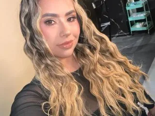 MaraMoore poses for a selfie with her long blonde wavy hair flowing over her black top.