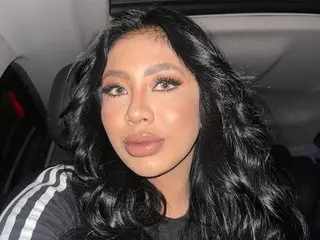 Mariana_Ferreira poses with long, wavy black hair and a direct gaze, showing her face and shoulders in a close-up shot.